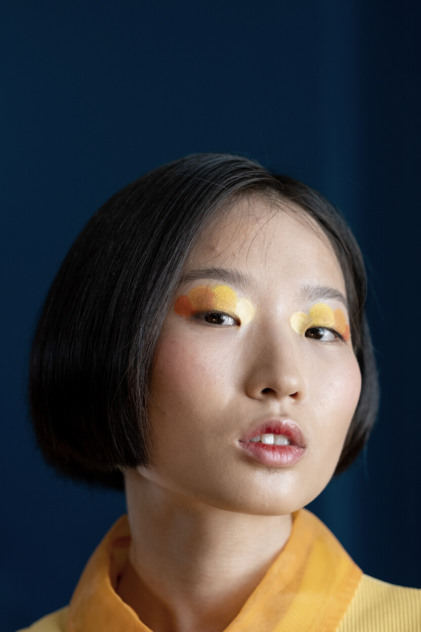 A Headshot of a Female Wearing Creative Make Up and Looking at Camera 
